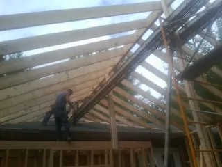 Rafters going up over a new addition with a worker on the wall in Sun City